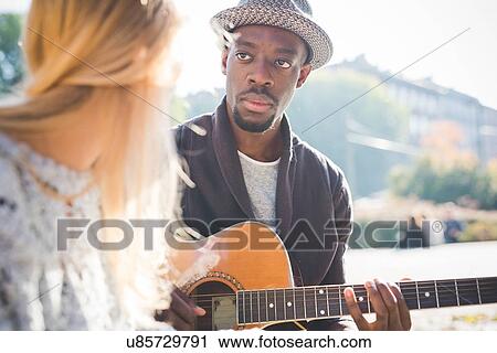 Stock Image - Couple learning to play guitar in park. Fotosearch