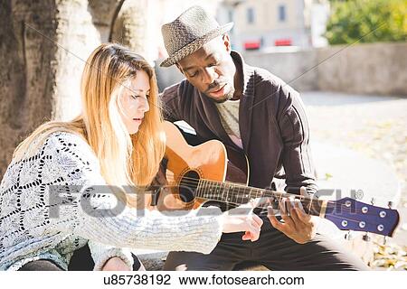 Couple learning to play guitar in park View Large Photo Image Stock Image - Couple learning to play guitar in park. Fotosearch