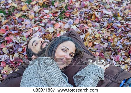 Couple lying on autumn leaves in garden View Large Photo Image Stock Photo - Couple lying on autumn leaves in garden. Fotosearch