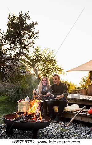 Couple sitting by fire pit in garden View Large Photo Image Stock Image - Couple sitting by fire pit in garden. Fotosearch
