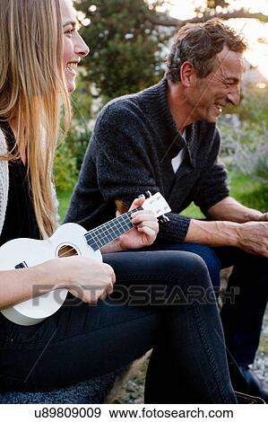 Couple sitting together, woman playing ukulele View Large Photo Image Stock Photo - Couple sitting together, woman playing ukulele. Fotosearch