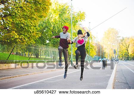Couple skipping on street View Large Photo Image Stock Photo - Couple skipping on street. Fotosearch