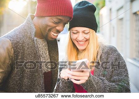 Couple smiling at message on smartphone View Large Photo Image Stock Photo - Couple smiling at message on smartphone. Fotosearch