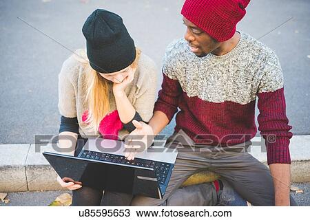 Couple using laptop on pavement View Large Photo Image Stock Image - Couple using laptop on pavement. Fotosearch
