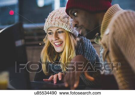 Stock Image - Couple using laptop outdoors at dusk. Fotosearch