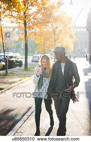 Stock Image - Couple walking on pavement. Fotosearch