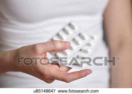Stock Photo - Cropped close up of young woman holding two medicine blister packs. Fotosearch