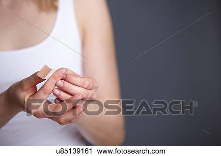 Cropped close up shot of young woman applying adhesive plaster to her own finger View Large Photo Image Stock Image - Cropped close up shot of young woman applying adhesive plaster to her own finger. Fotosearch