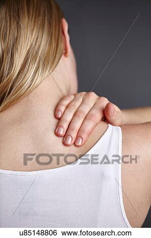 Stock Photograph - Cropped close up shot of young womans hand massaging her own shoulder. Fotosearch