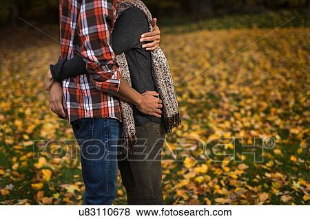Stock Photo - Cropped shot of mid adult couple hugging in autumn forest. Fotosearch