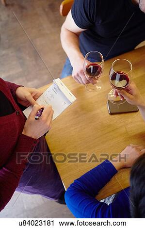 Stock Image - Cropped shot of waitress taking order in restaurant from couple. Fotosearch