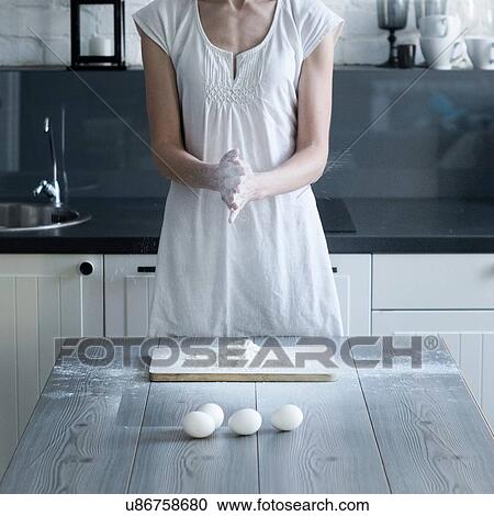 Stock Image - Cropped shot of woman baking with flour at kitchen table. Fotosearch