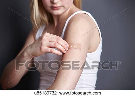 Cropped shot of young woman applying adhesive plaster to her own arm View Large Photo Image Stock Image - Cropped shot of young woman applying adhesive plaster to her own arm. Fotosearch