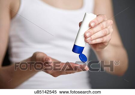 Stock Photography - Cropped shot of young woman holding tube of moisturiser. Fotosearch