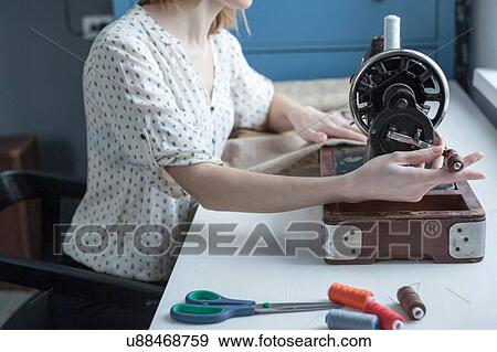 Stock Photo - Cropped view of woman sewing on vintage sewing machine. Fotosearch
