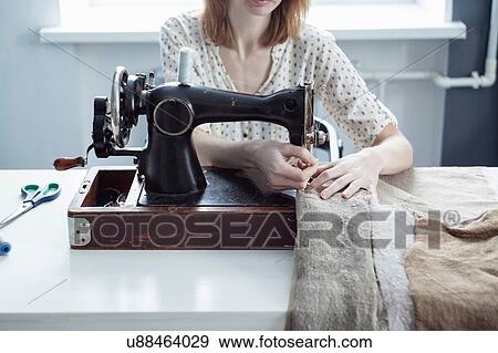 Stock Photo - Cropped view of woman sewing textiles on vintage sewing machine. Fotosearch
