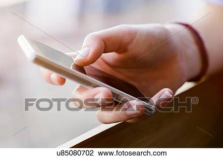 Stock Image - Cropped view of young womans hands using smartphone. Fotosearch