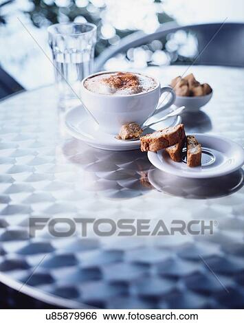 Stock Photograph - Cup of cappuccino, biscotti on table. Fotosearch