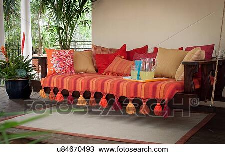 Stock Image - Cushion covered swing seat on porch. Fotosearch