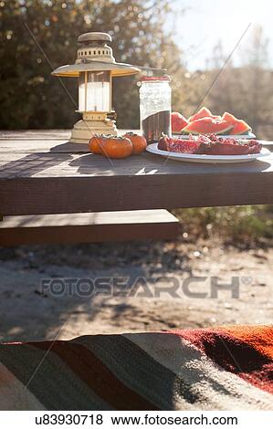 Stock Photo - Cut fruit on plate on picnic table. Fotosearch