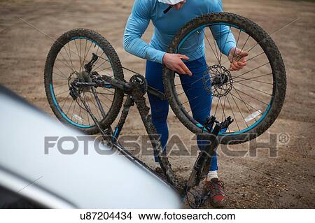 Picture - Cyclist fitting bicycle wheel to upside down bicycle. Fotosearch