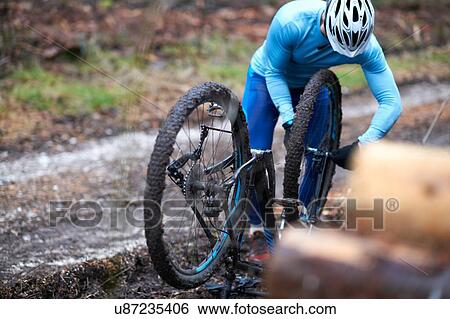 Cyclist wearing bicycle helmet repairs upside down bicycle View Large Photo Image Stock Photograph - Cyclist wearing bicycle helmet repairs upside down bicycle. Fotosearch