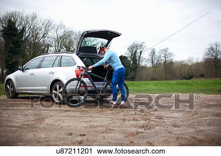 Cyclist wearing bicycle helmet unloading bicycle from car boot View Large Photo Image Stock Image - Cyclist wearing bicycle helmet unloading bicycle from car boot. Fotosearch