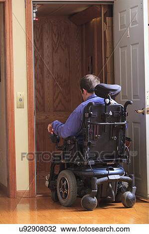 Stock Image - Disabled man entering a home elevator. Fotosearch