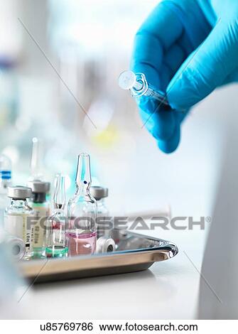 Doctor placing syringe back onto tray with drug vials View Large Photo Image Stock Photograph - Doctor placing syringe back onto tray with drug vials. Fotosearch