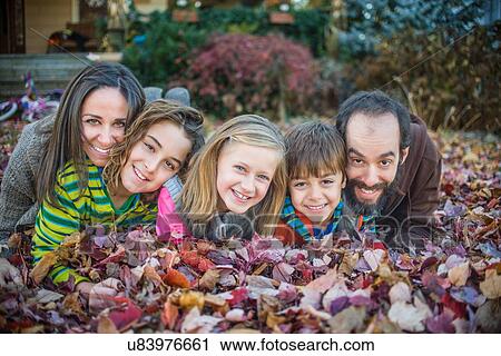 Family lying on autumn leaves in garden View Large Photo Image Stock Image - Family lying on autumn leaves in garden. Fotosearch