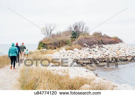Stock Image - Family walking along pathway beside lake. Fotosearch