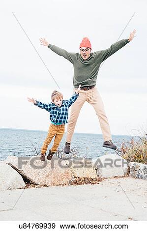Father and son jumping off of rocks beside lake View Large Photo Image Stock Photo - Father and son jumping off of rocks beside lake. Fotosearch