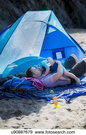 Father holding son in a tent on beach View Large Photo Image Stock Photo - Father holding son in a tent on beach. Fotosearch