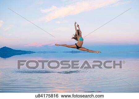 Stock Photograph - "Female ballet dancer jumping mid air over lake, Bonneville Salt Flats, Utah, USA". Fotosearch