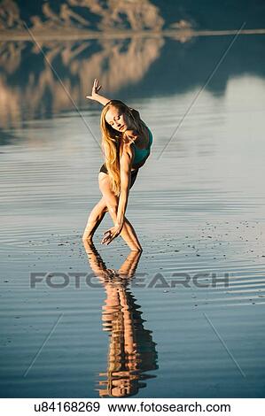 Stock Photo - "Female ballet dancer poised bending forward in lake, Bonneville Salt Flats, Utah, USA". Fotosearch
