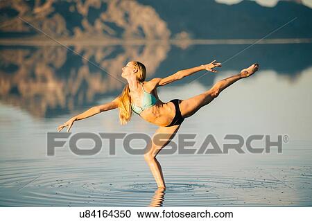 Stock Image - "Female ballet dancer poised on one leg in lake, Bonneville Salt Flats, Utah, USA". Fotosearch