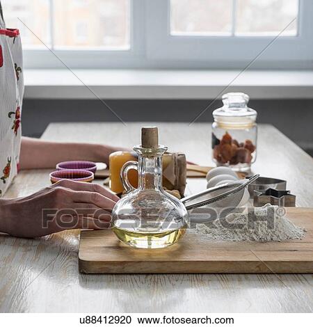 Stock Image - Female hands preparing raw ingredients for baking at kitchen counter. Fotosearch