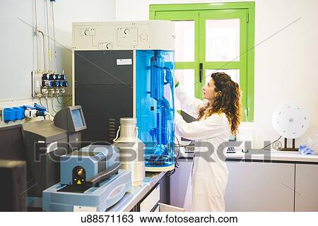 Stock Image - Female scientist measuring the surface area of mesoporous materials with BET instrument. Fotosearch
