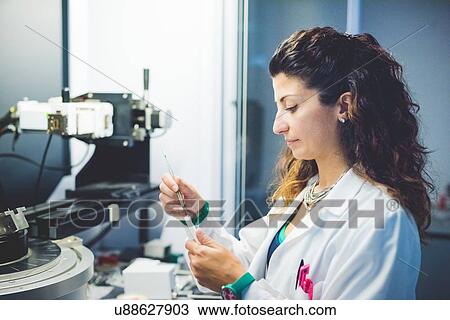 Stock Image - Female scientist preparing thin film sample for measurement with x-ray diffractometer. Fotosearch