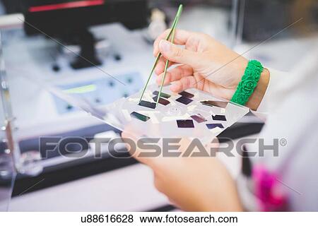 Stock Photo - Female scientist using FTIR spectrophotometer, taking thin film sample for measurement. Fotosearch