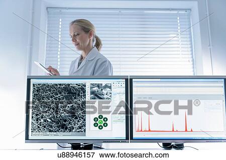Stock Photo - Female scientist with electron microscope screens. Fotosearch
