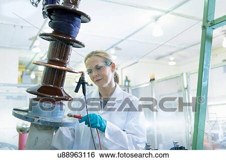 Stock Photograph - Female worker inspecting electrical insulator from power distribution network. Fotosearch