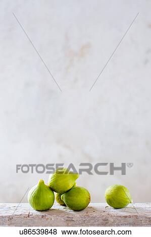Stock Photo - Five fresh figs stacked on rustic wooden plank. Fotosearch