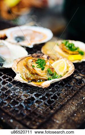 Stock Image - Food stall with grilled scallops, lemon and spring onions, Japan. Fotosearch