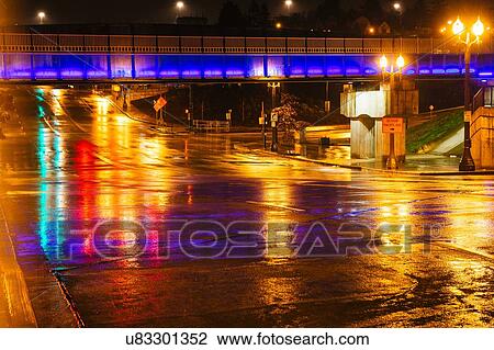 Stock Image - "Footbridge over wet city road at night, Tacoma, Washington, USA". Fotosearch