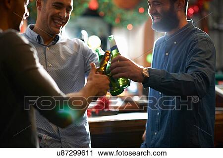 Stock Image - Friends in public house making a toast. Fotosearch