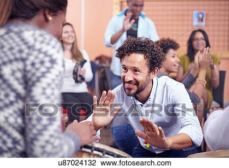 Stock Image - Friends playing musical instruments and dancing, smiling. Fotosearch