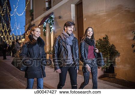Friends walking down street in the evening smiling View Large Photo Image Stock Photo - Friends walking down street in the evening smiling. Fotosearch