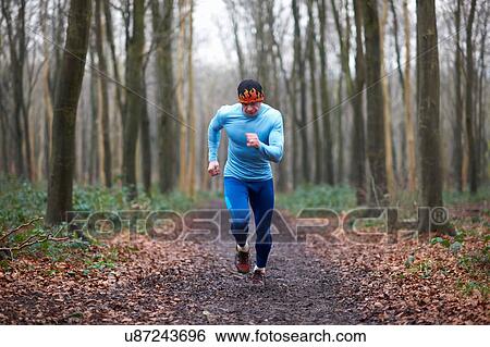 Stock Photograph - Full length front view of runner on tree lined path looking down. Fotosearch