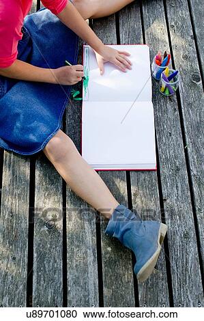 Stock Image - Girl drawing picture, high angle view. Fotosearch